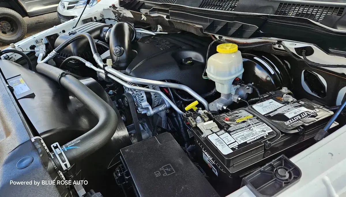 A technician working under the hood of a pickup truck in a repair shop