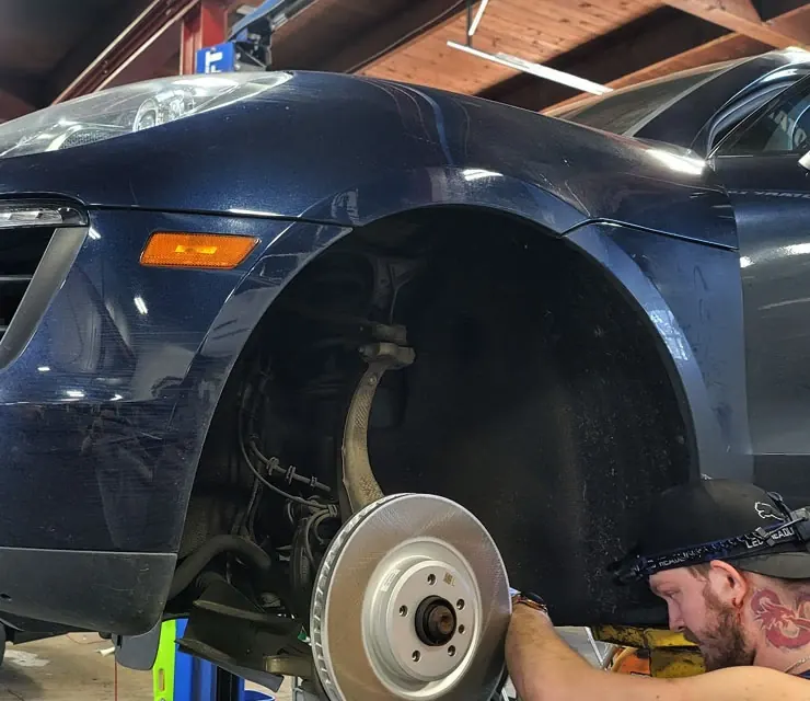 A new front brake rotor fitted on a navy sports coupe in a repair shop